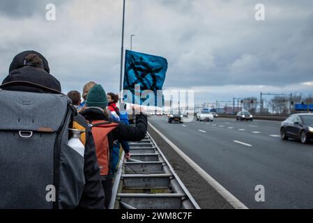 Amsterdam, Nordholland, Niederlande. Februar 2024. Aktivisten warten auf die Verkehrsabnahme, bevor sie auf die Autobahn A10 überqueren. Am 24. Februar 2024 blockierten Aktivisten die A10, eine Hauptstraße in Amsterdam, Niederlande. Ihre Forderung lautete, dass die ING Bank ihre Investitionen in die fossile Brennstoffindustrie einstellen sollte. (Kreditbild: © James Petermeier/ZUMA Press Wire) NUR REDAKTIONELLE VERWENDUNG! Nicht für kommerzielle ZWECKE! Stockfoto