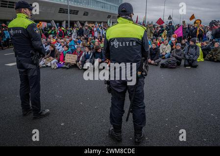 Amsterdam, Nordholland, Niederlande. Februar 2024. Die niederländische Polizei umgibt eine Gruppe von Aktivisten, die die Autobahn A10 blockieren. Am 24. Februar 2024 blockierten Aktivisten die A10, eine Hauptstraße in Amsterdam, Niederlande. Ihre Forderung lautete, dass die ING Bank ihre Investitionen in die fossile Brennstoffindustrie einstellen sollte. (Kreditbild: © James Petermeier/ZUMA Press Wire) NUR REDAKTIONELLE VERWENDUNG! Nicht für kommerzielle ZWECKE! Stockfoto