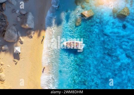 Aerial view of boat, sandy beach, blue sea with waves at sunset Stockfoto