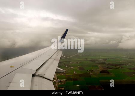 Blick aus dem Fenster des Kombi-Flugzeugs über den Flügel des Air France/KLM-Jets, der in den bewölkten Randbezirk von Paris, Frankreich, absteigt Stockfoto