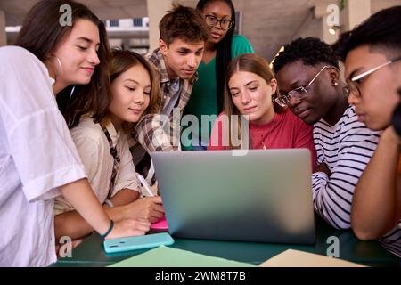 Gruppe junger Klassenkameraden, die gemeinsam mit einem Laptop im Klassenzimmer auf dem Universitätscampus studieren Stockfoto