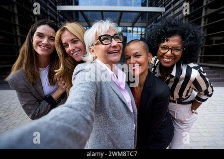 Gruppe verschiedene Business formelle Frauen, die Selfie mit Handy machen und lächelnd in die Kamera schauen. Stockfoto