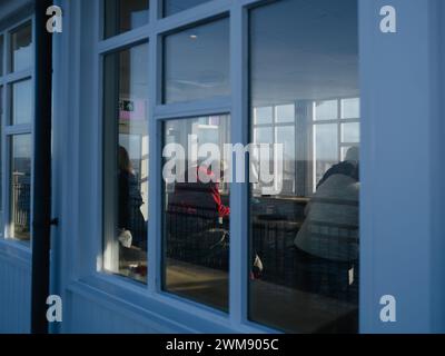 Älterer Mann in einem roten Pullover, der in einem Café sitzt - Southwold, Suffolk England Stockfoto