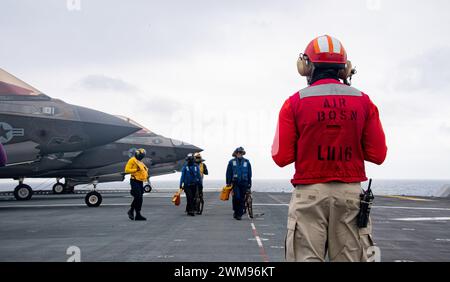 PACIFIC OCEAN (16. Februar 2024) LT J.G. Keji Alinadarijo, rechts, aus Chicago, der dem vorgelagerten amphibischen Angriffsträger USS America (LHA 6) zugeteilt wurde, beobachtet am 16. Februar Seeleute, die Flugoperationen im Pazifischen Ozean durchführen. America, Leitschiff der America Amphibious Ready Group, ist im Einsatzgebiet der 7. US-Flotte im Einsatz. Die 7. US-Flotte ist die größte nach vorne gerichtete nummerierte Flotte der US Navy und interagiert routinemäßig mit Verbündeten und Partnern, um eine freie und offene Region im Indo-Pazifik zu erhalten. (Foto der U.S. Navy von Mass Communication Specialist 2nd Cl Stockfoto