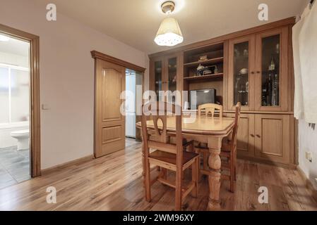 Ein Wohnzimmer mit einem maßgeschneiderten Sideboard aus Holz an einer Wand, Kastanienholzböden und einem Esstisch mit passenden Stühlen Stockfoto