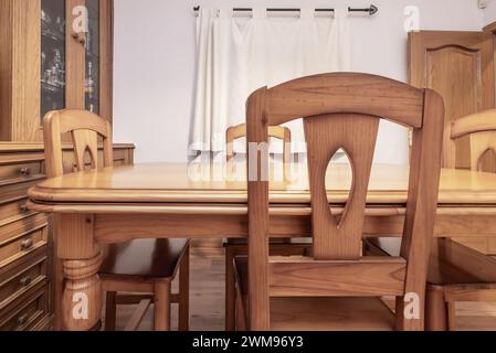 Ein Wohnzimmer mit einem maßgeschneiderten Sideboard aus Holz an einer Wand, Kastanienholzböden und einem Esstisch mit passenden Stühlen mit Stoffvorhängen auf dem Gewinn Stockfoto