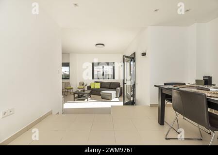 Wohnzimmer auf zwei Ebenen eines Einfamilienhauses mit glatten weiß lackierten Wänden und Metallschreinerei aus schwarzem Aluminium und Glasfenstern und -Türen Stockfoto