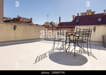 Ein Metall-Terrassentisch mit passenden Stühlen auf dem Dachboden eines Wohnhauses Stockfoto