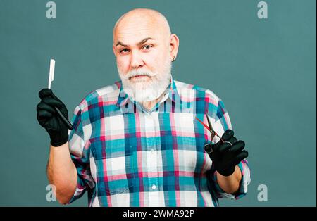Mann mittleren Alters, Friseur hält Friseur Ausrüstungen, isoliert auf grauem Hintergrund. Friseurladen Barbershop Konzept. Haarbehandlung für Männer. Stockfoto