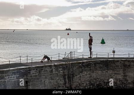 Ein junger Mann mit Sir Anthony Gormleys „Look II“-Skulptur am West Hoe Pier Plymouth, der Exekutienten oder Kunstverehrung anbetet. Die Kontroverse Stockfoto