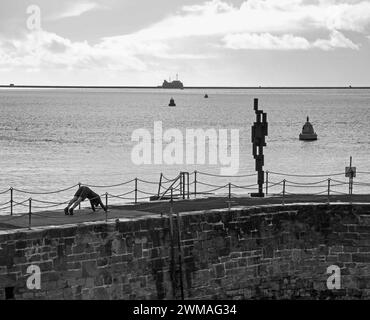 Ein junger Mann mit Sir Anthony Gormleys „Look II“-Skulptur am West Hoe Pier Plymouth, der Exekutienten oder Kunstverehrung anbetet. Die Kontroverse Stockfoto