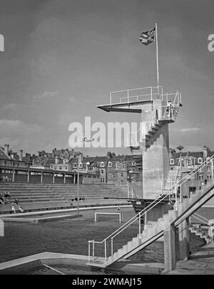 Ein Mann taucht von den Brettern im Hastings St. Leonards Bade Pool, Seaside Road, St. Leonards-on-Sea, East Sussex, England, UK c.1950. Der beeindruckende lido wurde 1933 eröffnet. Das Schwimmbad wurde von Sidney Little entworfen und gebaut, dem Borough Engineer. Der riesige Pool war 15 Meter tief unter der Betontauchplattform. Im Pool gab es viele Schwimm- und Tauchveranstaltungen sowie Mode- und Schönheitsshows. Da Pauschalreisen im Ausland immer beliebter wurden, gingen die Badezahlen zurück und der Pool wurde 1959 geschlossen. Es wurde ein Ferienlager (1960–86). Sie wurde 1993 abgerissen. Stockfoto