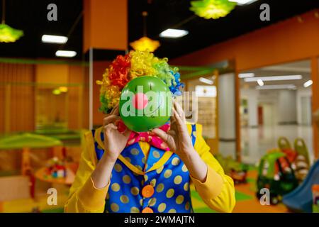 Lustiger, verspielter Clown, der ein Gesicht mit niedlicher Grimasse auf Ball macht Stockfoto
