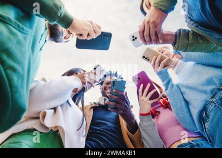 Gruppe junger Erwachsener, die mit ihren Smartphones interagieren und Inhalte teilen – soziale Konnektivität und Nutzung von Technologien im modernen Lebensstil Stockfoto