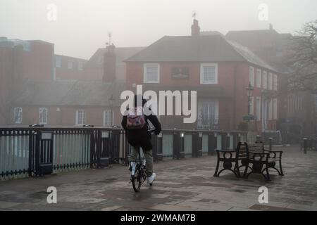 Windsor, Berkshire, Großbritannien. Februar 2024. Ein Radfahrer überquert die Windsor Bridge im Nebel. Heute war es ein nebeliger Morgen in Windsor, Berkshire, aber der Sonnenschein verbrannte schnell den Nebel und Nebel. Quelle: Maureen McLean/Alamy Live News Stockfoto