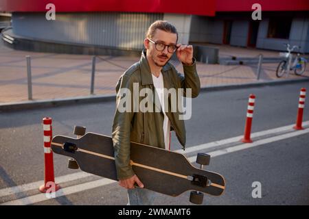 Porträt eines gutaussehenden lässigen Mannes mit Skateboard über Downtown Hintergrund Stockfoto