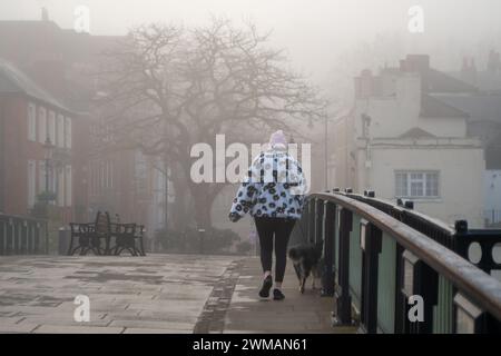 Windsor, Berkshire, Großbritannien. Februar 2024. Ein Fußgänger überquert die Windsor Bridge im Nebel. Heute war es ein nebeliger Morgen in Windsor, Berkshire, aber der Sonnenschein verbrannte schnell den Nebel und Nebel. Quelle: Maureen McLean/Alamy Live News Stockfoto