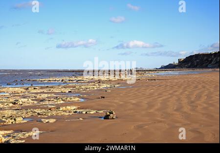 Ein Blick auf den Strand bei Niedrigwasser während einer Flut mit Menschen, die an der Küste von West Runton, Norfolk, England, Vereinigtes Königreich laufen. Stockfoto
