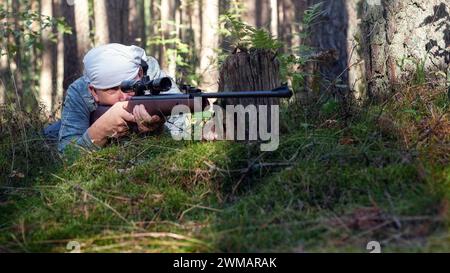 Ein junger Kerl bereitet sich darauf vor, aus einer pneumatischen Waffe zu schießen. Stockfoto