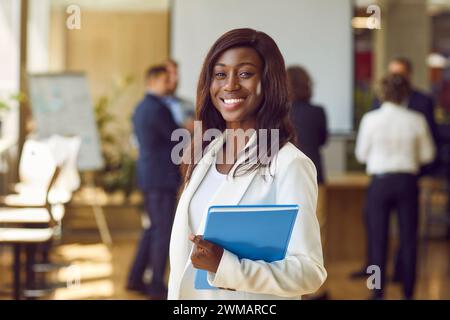 Glücklich lächelnde afroamerikanerin, die in die Kamera blickt und im Büro lächelt. Stockfoto