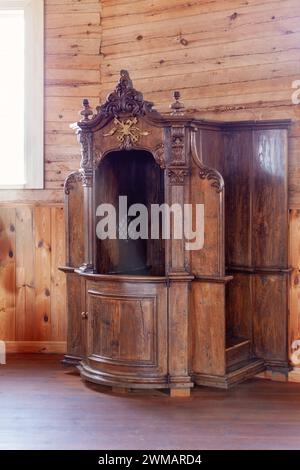 Ein hölzerner Beichtstuhl im Inneren einer Holzkirche. Authentischer Beichtstuhl aus der alten Kirche von Sasnava. Stockfoto