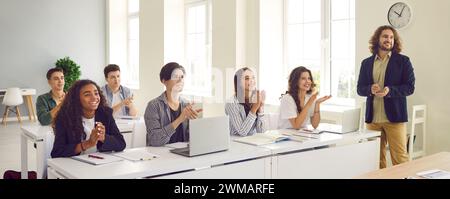 Freudig aufgeregte Studenten applaudieren nach erfolgreichem Vortrag des Lehrers. Stockfoto