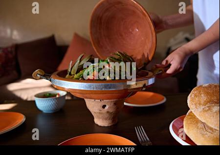 Stillleben. Marokkanischer Tagine. Hausfrau serviert köstliche vegetarische Gerichte mit gedämpftem Gemüse, zubereitet in Tontopf nach traditionellem marokkanischem Vorbild Stockfoto