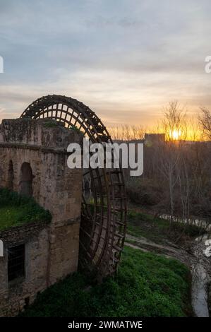 Die Sonne erhebt sich über einem großen stillgelegten mittelalterlichen, strukturierten Wasserrad aus Holz, das als Molino de la Albolafia am Ufer des Guadalquivir bekannt ist Stockfoto