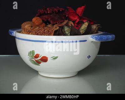 Ein Pot-pourri-Arrangement, dessen Inhalt aus getrockneten, natürlich duftenden Pflanzenmaterialien wie Samenkapseln und Blütenblättern in einer Faience de Quimper-Schüssel gewonnen wird. Stockfoto