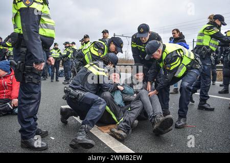 Die Polizei hält einige Demonstranten fest, während sie die Autobahn A10 während des Umweltschutzprotests am 24. Februar 2024 in Amsterdam blockierten. Mitglieder der Extinction Rebellion fordern sofortige Einstellung der Finanzierung der fossilen Industrie. Über 300 Demonstranten der Extinction Rebellion blockierten die Autobahn A10 in Amsterdam. Die Polizei entfernte alle Demonstranten innerhalb von 2 Stunden und verhaftete über 300.die Aktion protestierte gegen Subventionen für fossile Brennstoffe und die Klimapolitik der Regierung.beteiligte Fahrzeuge beschlagnahmt, Straße zwischen de Nieuwe Meer und Oud-Zuid wieder eröffnet. Foto: Taim Mouneb/ABACAPRESS.COM Stockfoto