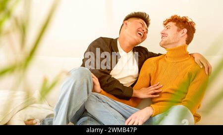 Schwule Paare lachen, während sie auf dem Sofa sitzen Stockfoto