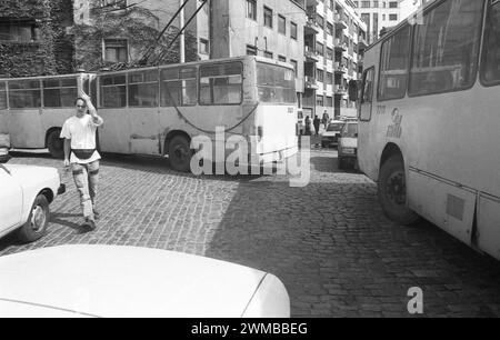 Bukarest, Rumänien, 1990. Eine Person überquert eine Nachbarschaftsstraße, während einige Trolleybusse abbiegen. Stockfoto