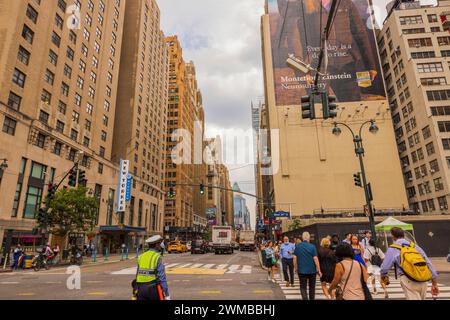 Blick auf einen Polizeibeamten des NYPD am Broadway in Manhattan, der den Verkehr vor einer Fußgängerüberfahrt mit Menschen reguliert. NEW YORK USA. Stockfoto