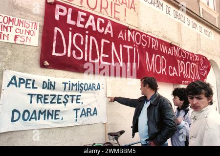 Brasov, Rumänien, April 1990. Nach der antikommunistischen Revolution von 1989 brachen im ganzen Land Proteste gegen die ehemaligen kommunistischen Beamten aus, die sofort die Macht ergriffen hatten. Auf dem zentralen Platz von Brasov lesen die Menschen Plakate und Transparente, die die neue Partei an der Macht, F.S.N., verurteilten Stockfoto