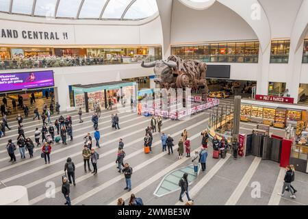 Kunden und Passagiere am Bahnhof Birmingham New Street, gehen und stehen im Hauptfoyer mit Ozzy, dem tobenden Bullen. Stockfoto