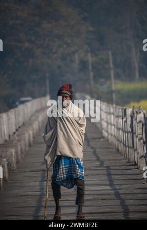 Ein Mann geht an einem Wintermorgen durch die Brücke und hält einen Bambusstock Stockfoto