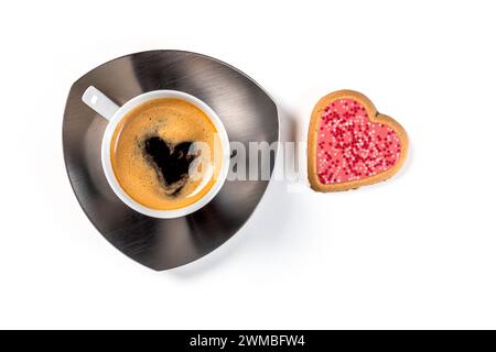 Eine Tasse Kaffee auf einer Untertasse mit einem herzförmigen Keks in rosa Glasur. Draufsicht auf weißem Hintergrund. Stockfoto