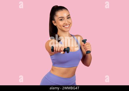 Lächelnde junge Frau, die mit Kurzhanteln trainiert Stockfoto