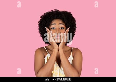 Playful African American woman with curly hair making a funny face with puffed cheeks Stockfoto