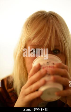 Frau trinkt Kaffee aus einer Einweg- oder recycelbaren Tasse, Nahaufnahme, Fokus auf die Augen Stockfoto