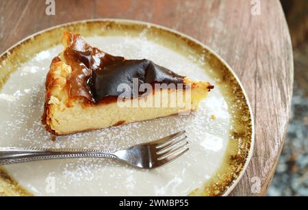 Ein Stück leckerer baskischer Käsekuchen auf einem Holztisch Stockfoto
