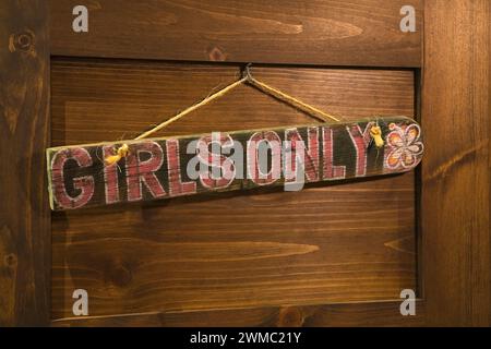 Rot gemalte Mädchen bemerken nur Schild an braun gebeizter Holztür im luxuriösen skandinavischen Haus aus Holz und Holz. Stockfoto