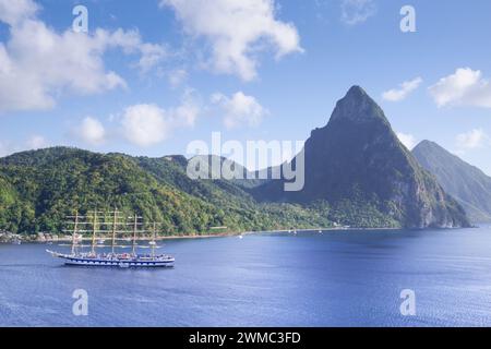 Die berühmten Pitons von Saint Lucia, mit einem Segelboot, das Soufriere im Vordergrund überquert (St. Lucia, Westindien) Stockfoto