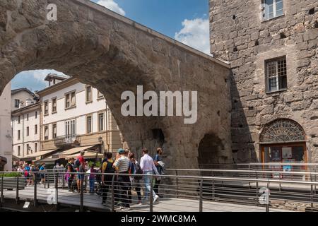 Touristen überqueren das Pretoria-Tor (25 v. Chr.), das römische Stadttor, das von zwei Bögen gebildet wird, die einen Paradeplatz umschließen, Aosta, Aosta-Tal, Italien Stockfoto