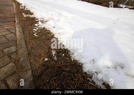 Schmelzender Schnee am Straßenrand am Bordstein Stockfoto