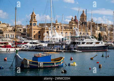 Ein traditionelles Luzzu steht im Gegensatz zu Luxusyachten in Vittoriosa Yacht Marina - ein Blick über den Hafen von Senglea, Valletta, Malta Stockfoto