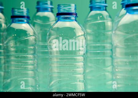 Nahaufnahme offener transparenter wiederverwendbarer Kunststoffflaschen, die nach dem Recycling wiederverwendet werden können, auf mintgrünem Hintergrund Stockfoto