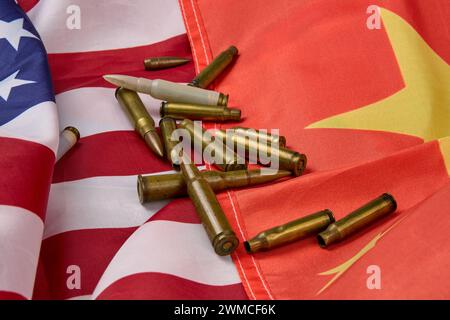 Nahaufnahme von Patronen und Kugeln unterschiedlicher Größe, die auf der amerikanischen und chinesischen Flagge angeordnet sind. Stockfoto