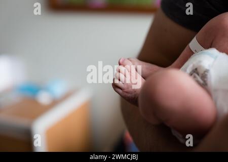 Nahaufnahme eines Mannes, der in einem Krankenhauszimmer steht und seinen neugeborenen Sohn hält Stockfoto