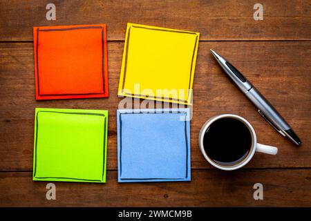 Set aus bunten, leeren Erinnerungsnotizen auf einem Grunge-Holztisch mit einer Tasse Espresso und Stift Stockfoto